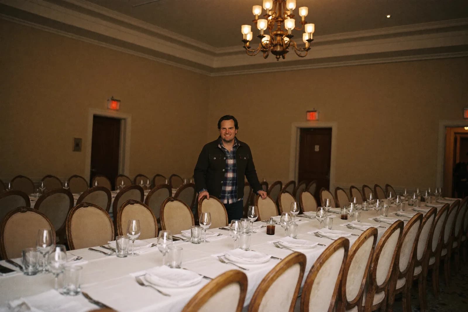 An owner straightening chairs in a set banquet hall an hour before the doors.