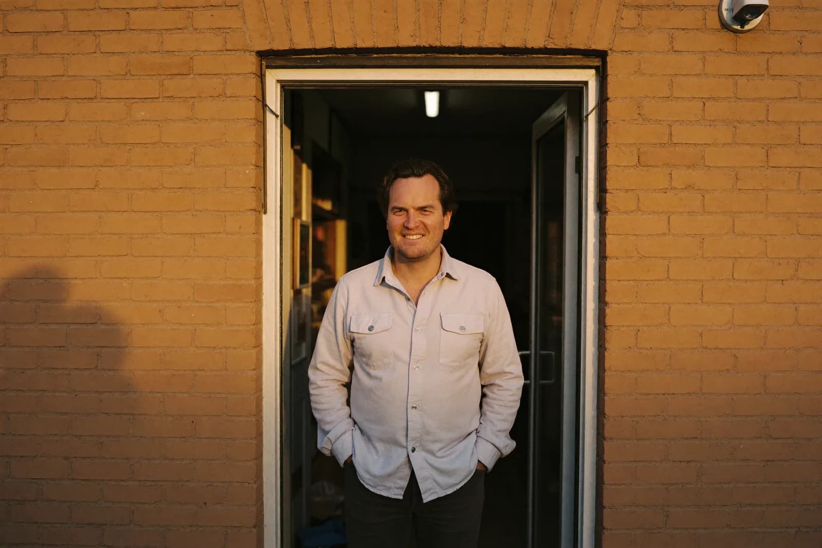 An owner standing in his shop doorway at golden hour.